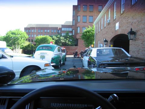 1991 Ford LTD Crown Victoria - View through a car windshield of green-and-white Sheriff cars and police motorcycles gathered in a brick courtyard.