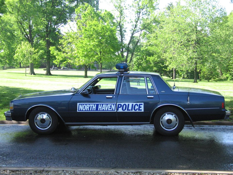 Dark blue North Haven Police sedan in profile parked in a leafy park