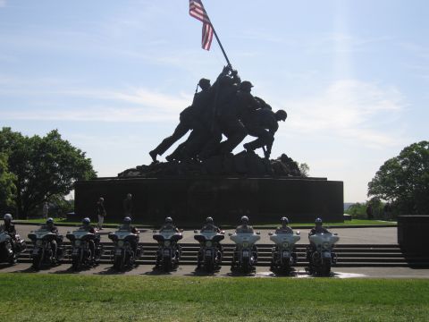 1991 Ford LTD Crown Victoria - Police motorcycles lined up on pavement in front of the bronze Iwo Jima Marine Corps Memorial with a U.S. flag flying.
