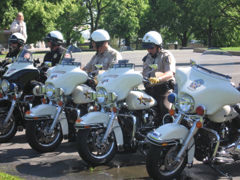 1991 Ford LTD Crown Victoria - line of white police touring motorcycles stands in a parking lot as uniformed officers in white helmets prepare to mount them.