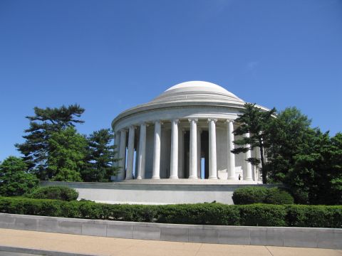 1991 Ford LTD Crown Victoria - white domed neoclassical memorial ringed by tall columns sits among trees and trimmed hedges under a clear blue sky.