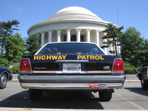 1991 Ford LTD Crown Victoria - rear view of a black Ford Crown Victoria Highway Patrol car with California plate, parked before a columned white domed memorial.