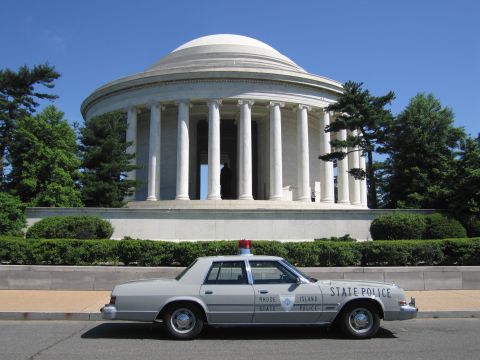 1991 Ford LTD Crown Victoria - gray Rhode Island State Police sedan with a red roof beacon sits before the domed, columned Jefferson Memorial under a blue sky.