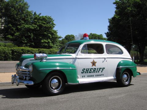 1991 Ford LTD Crown Victoria - restored vintage green-and-white two-door Ford Sheriff car marked St. Johns County, with a red roof beacon and spotlight.