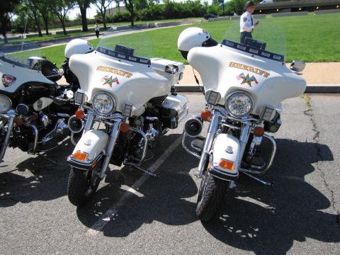 1991 Ford LTD Crown Victoria - Two white police motorcycles marked Sheriff with a star emblem and helmets resting on the windshields in a parking lot.