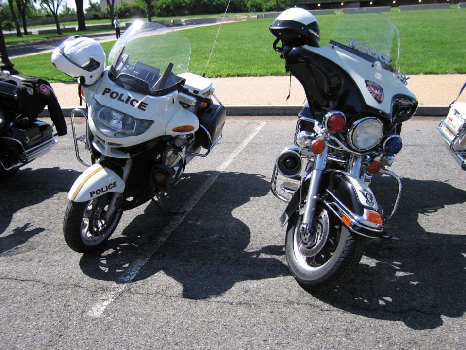 Two police motorcycles, one white and one black, parked side by side