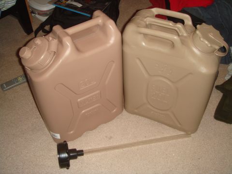 1992 Ford Bronco - Two tan military-style 20-liter plastic jerry cans standing side by side on carpet, one molded WATER, the other FUEL with Arabic script, wi…