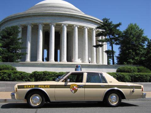 1991 Ford LTD Crown Victoria - tan four-door State Police sedan with roof beacon photographed in profile in front of the columned Jefferson Memorial.