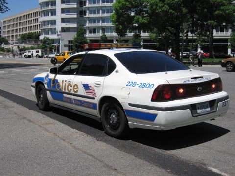 1991 Ford LTD Crown Victoria - white and blue United States Capitol Police Chevrolet Impala patrol sedan parked at a curb with brake lights lit.