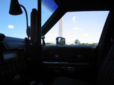 1991 Ford LTD Crown Victoria - Interior shot showing the dashboard, radio gear and side mirror of a car with the Washington Monument visible outside.