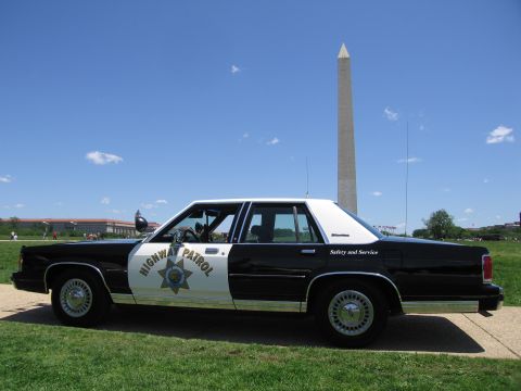 1991 Ford LTD Crown Victoria - Side profile of a black-and-white Highway Patrol sedan parked on a path with the Washington Monument behind it.