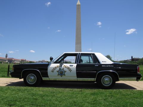 1991 Ford LTD Crown Victoria - Side view of a black-and-white Highway Patrol sedan parked on a path with the Washington Monument rising behind.