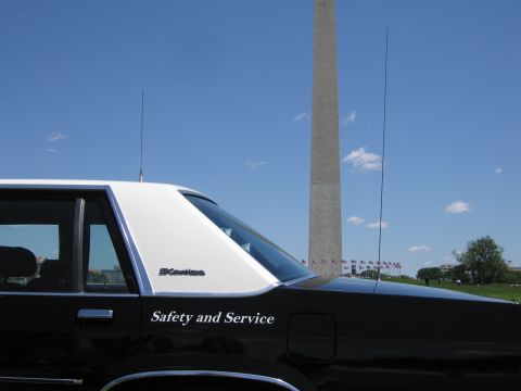 1991 Ford LTD Crown Victoria - Close view of a black-and-white police car's rear quarter showing a "Crown Victoria" badge and "Safety and Service" text.