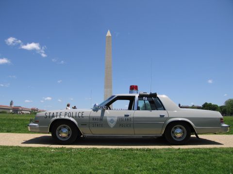 1991 Ford LTD Crown Victoria - silver Rhode Island State Police sedan with roof light bar sits in profile before the Washington Monument.