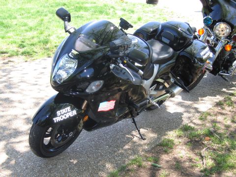 1991 Ford LTD Crown Victoria - black State Trooper sportbike with a US flag decal is parked on pavement, with a chromed cruiser motorcycle behind it.