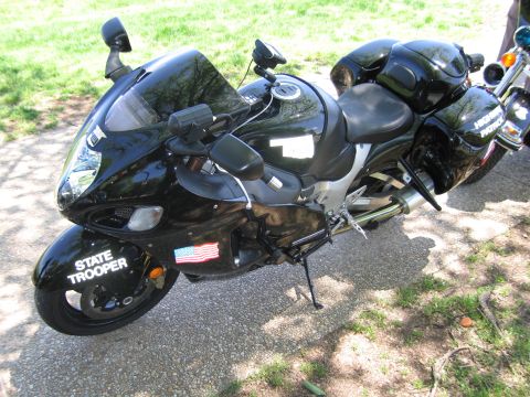 1991 Ford LTD Crown Victoria - black State Trooper sportbike fitted with saddlebags and a US flag decal stands on a paved path beside grass.