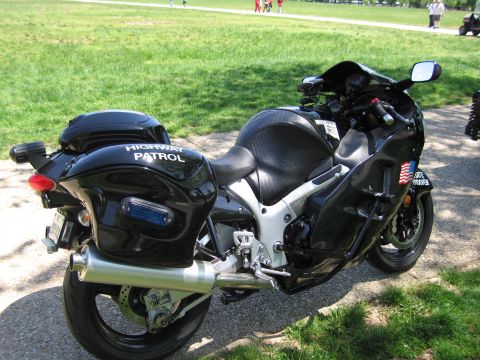 1991 Ford LTD Crown Victoria - black Highway Patrol sportbike with hard saddlebags and a chrome exhaust is parked on a path beside a grassy lawn.