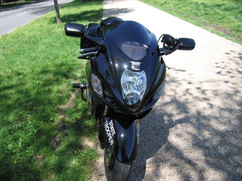 1991 Ford LTD Crown Victoria - glossy black sportbike with State Trooper lettering on the fairing faces forward, parked on a shaded paved path.