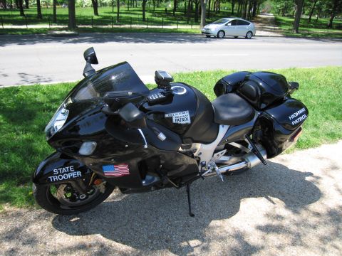 1991 Ford LTD Crown Victoria - black State Trooper sportbike marked Oklahoma Highway Patrol with saddlebags is parked beside a road and grass.