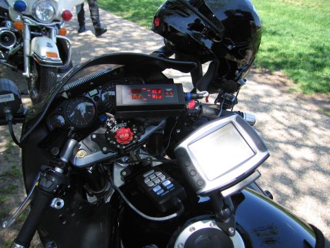 1991 Ford LTD Crown Victoria - handlebar area of a black police sportbike fitted with a digital radar display, switch panel, and mounted screen.