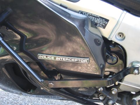 1991 Ford LTD Crown Victoria - Close-up of a black motorcycle side fairing bearing a Police Interceptor decal above the chrome frame and bracket.