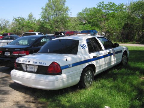 1991 Ford LTD Crown Victoria - white Ford Crown Victoria police K9 unit lettered United States Park Police parked on grass among other vehicles.