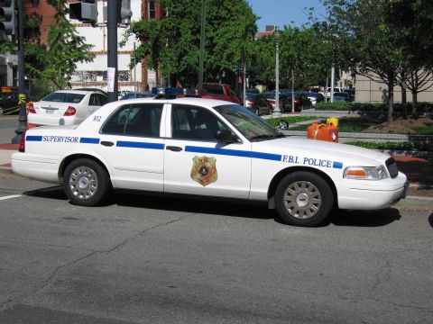 1991 Ford LTD Crown Victoria - white Ford Crown Victoria sedan lettered F.B.I. Police and Supervisor with blue stripe and badge parked at a corner.