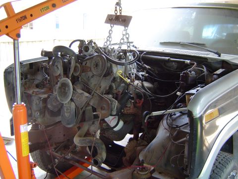 1986 Ford Bronco - Engine removal in progress for a 1986 Ford Bronco, with the V8 engine suspended by chains and an engine hoist.
