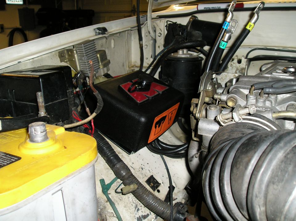 Engine bay with yellow top battery, black box, and engine components