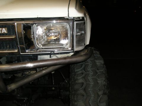 1986 Toyota Hilux - Front corner view of a white 1986 Toyota Hilux, a custom winch bumper and oversized tire.