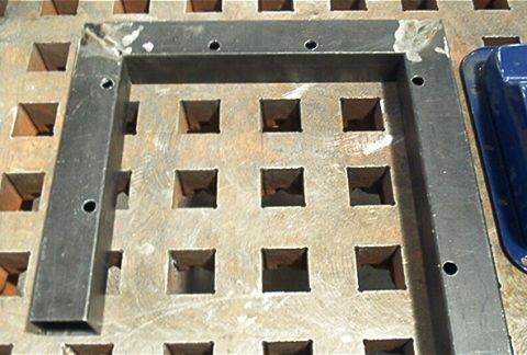 1986 Ford Bronco - A metal frame is positioned on a textured surface with a square grid pattern.