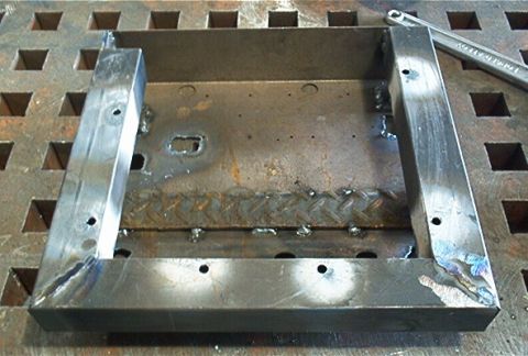1986 Ford Bronco - Custom metal bracket fabricated and placed on a workbench, with a wrench nearby.
