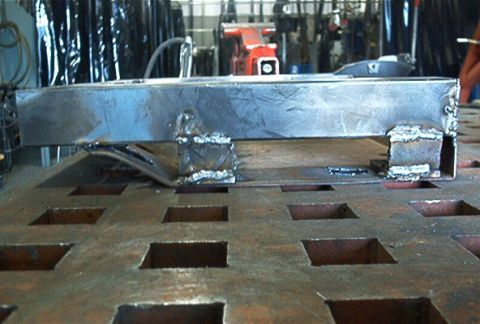 1986 Ford Bronco - A close-up of a custom metal part, likely for a vehicle, being worked on in a shop.