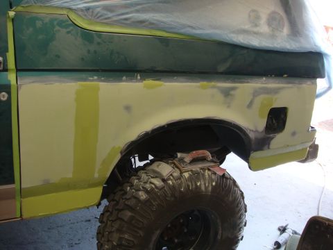 1996 Ford Bronco - Bodywork in progress on a green SUV's rear quarter panel, showing filler and masking tape.