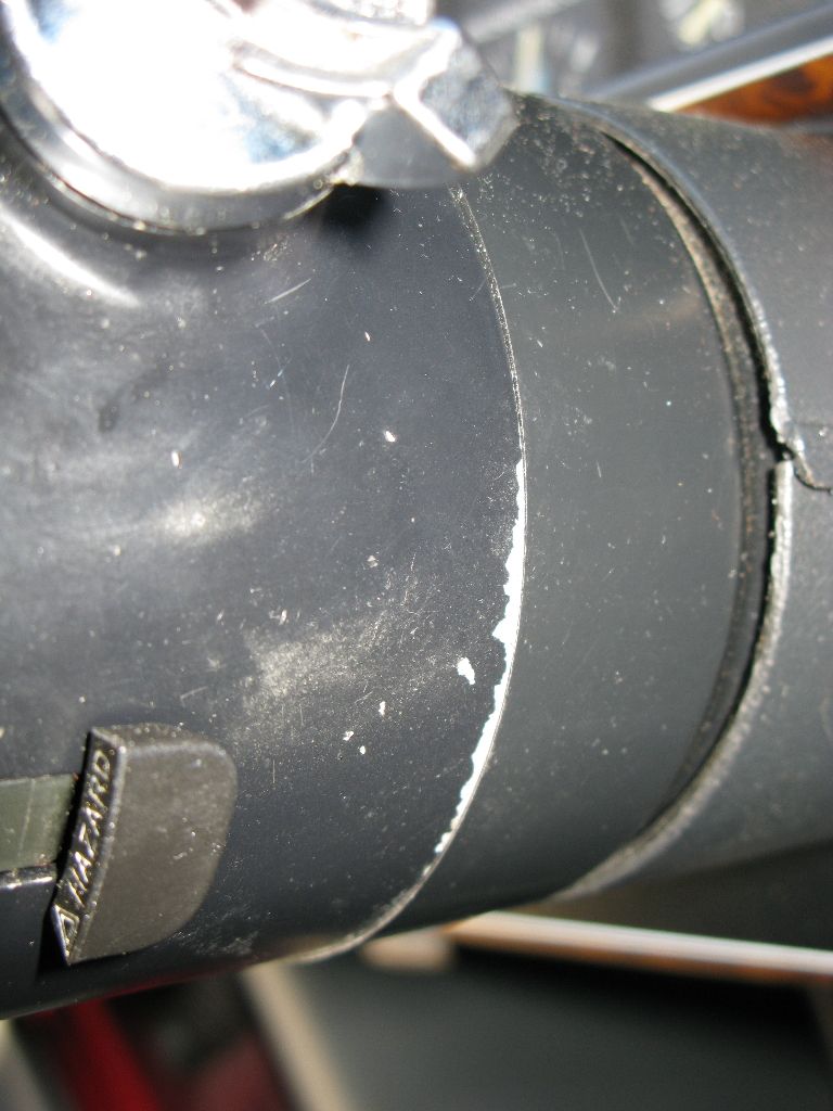 Close-up of a black steering column shroud with a hazard light button. White paint chips are visible