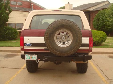 1992 Ford Bronco - The rear of a maroon and tan Ford Bronco is shown, a spare tire and a custom bumper.