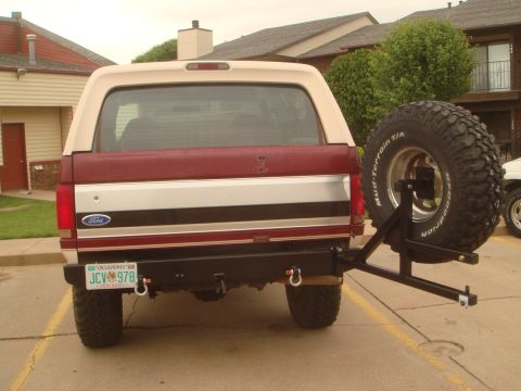 1992 Ford Bronco - The rear of a red and white Ford Bronco is visible, equipped with a spare tire carrier and a license plate.