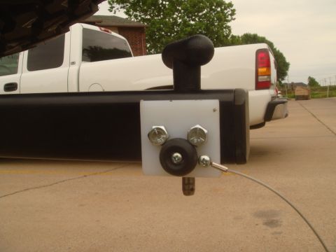 1992 Ford Bronco - Detail of a black tubular rear bumper end fitted with a white mounting plate, large chrome hex-nut bolts, a small black tow ball and a stee…