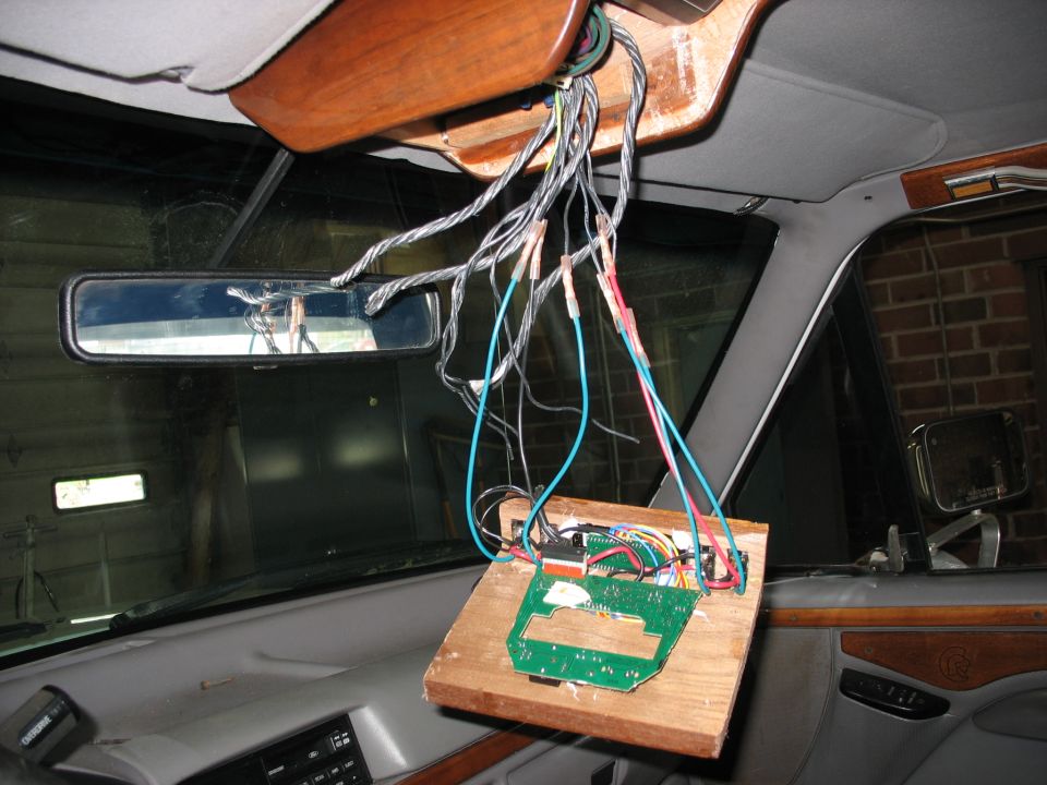 Overhead console dropped down with wiring harness and circuit board during install in truck cab