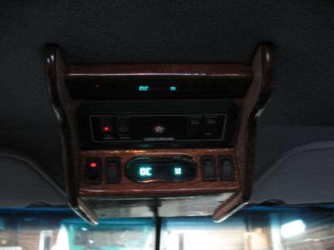 1995 Ford C-350 (Centurion Conversions) - The interior overhead console features wood grain trim and multiple switches, with a digital display.