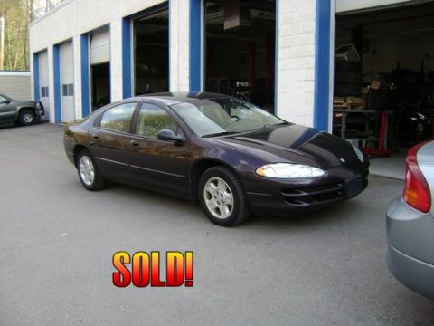 2001 Ford Crown Victoria - Dark purple sedan parked in front of a garage, with a silver car to the right. "SOLD!" text is on the ground.