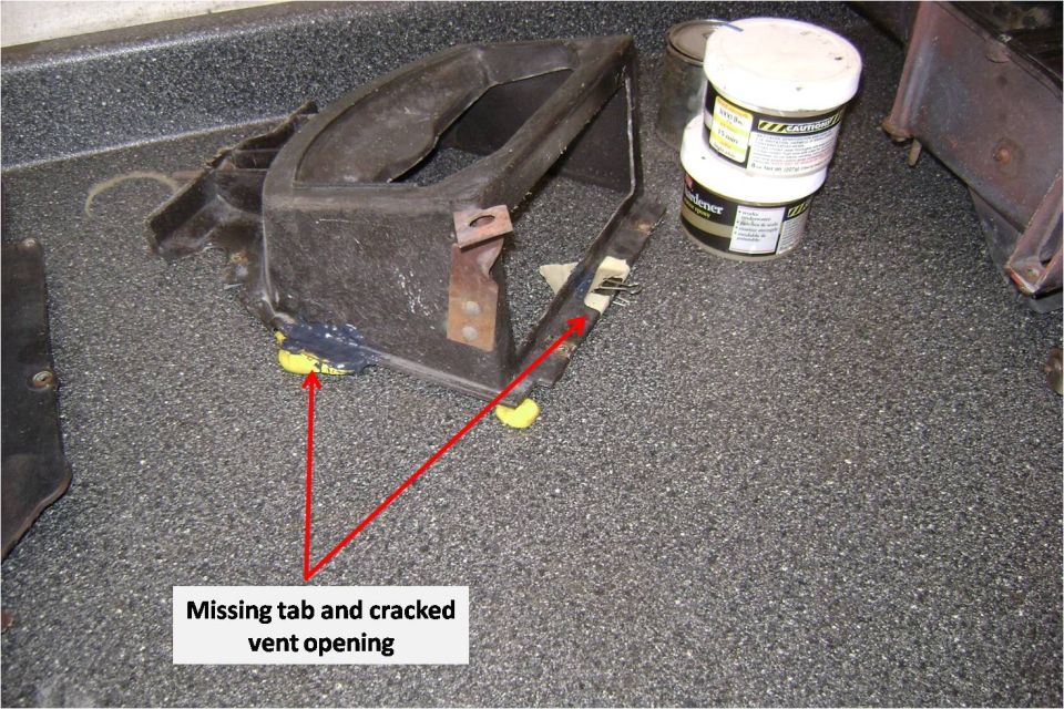 Black plastic vent housing with arrows labeling a missing tab and cracked opening