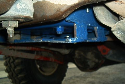 1986 Ford Bronco - The underside of a 1986 Ford Bronco, highlighting the blue painted skid plate and a portion of the tire.