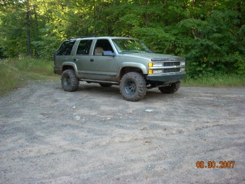 2000 Chevrolet Tahoe - This lifted SUV, likely from the mid-1990s, is shown off-road with aggressive tires and suspension modifications.