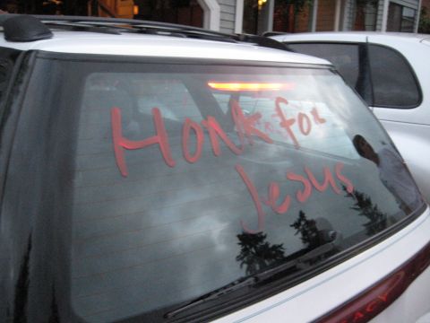 1980 Ford Bronco - The back window of a vehicle has red lettering that reads "Honk for Jesus".