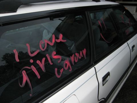 1980 Ford Bronco - Pink writing on the windows of a white station wagon reads "I Love Girls Group".