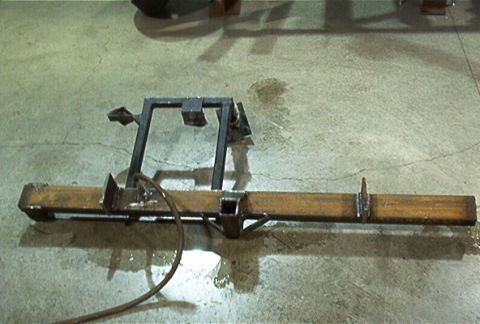 1986 Ford Bronco - A custom-fabricated steel bumper assembly, likely for an off-road vehicle, rests on a wet concrete surface.