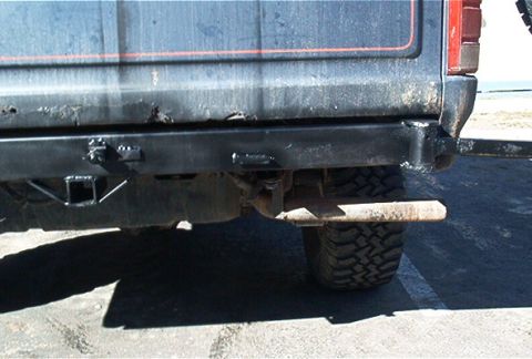 1986 Ford Bronco - The rear of a 1986 Ford Bronco shows a custom bumper with a tow hitch and a large off-road tire.