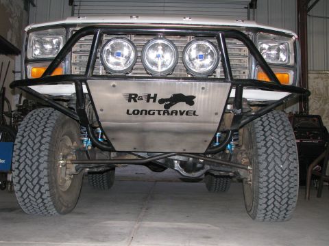 1980 Ford Bronco - Front view of a white Ford Bronco with a custom black off-road bumper and skid plate. The skid plate features a "R&H LONGTRAVEL" logo and t…