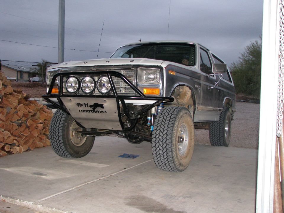 Modified 1980s Ford Bronco with custom bumper and large tires.